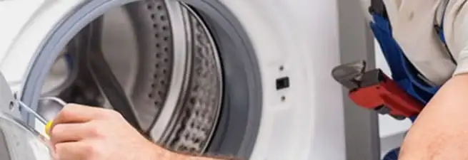 Appliance technician repairing a clothes dryer drum and internal parts in Boca Raton, FL