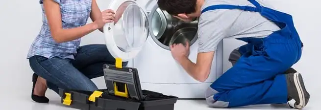 Washer repair technician inspecting a front-load washing machine with tools in Boca Raton, FL