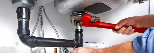 Garbage disposal repair technician tightening the sink drain and disposal connection in Boca Raton, FL