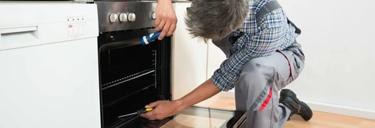 Oven repair technician inspecting and servicing an electric oven in Boca Raton, FL