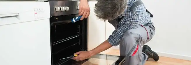 Oven repair technician inspecting and servicing an electric oven in Boca Raton, FL