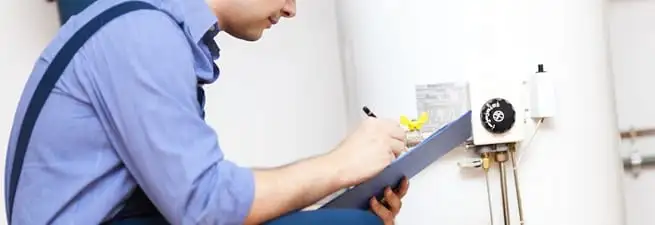 Water heater repair technician inspecting the unit and recording service notes in Boca Raton, FL